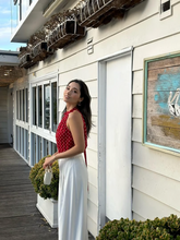 a lady wears a red polka dot printed halter top with white pants